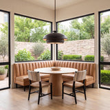 A mid-century dining room featuring a Garnett Large Pendant 24", Aged Iron suspended over a light wood table and a tan leather corner banquette.