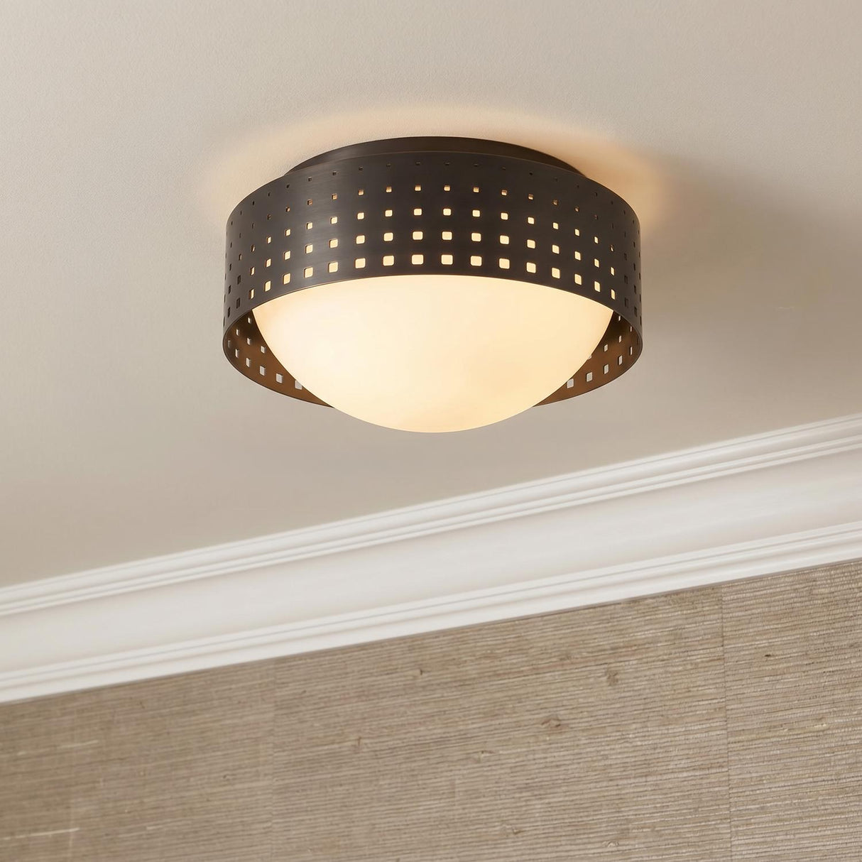 A transitional foyer with the Egan Small Flush Mount in urban bronze installed on a standard ceiling above tan grasscloth wallpaper and white crown molding.