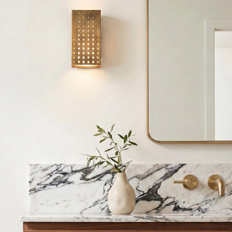A modern bathroom vanity featuring the vintage brass Egan LED Wall Sconce mounted beside a rounded mirror above a white marble backsplash with grey veining.
