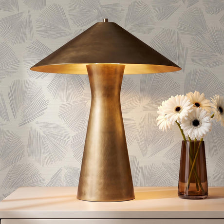 A modern living room with the Darnell Table Lamp 21", Vintage Brass on a white console table against gray fan patterned wallpaper and white flowers.