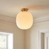 A traditional foyer with the Basile Small Semi-Flush 12", Brushed Brass and Ribbed Milk Glass along the ceiling near dentil crown molding and a white door.