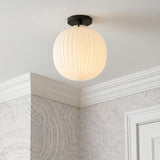 A contemporary foyer with a matte black and ribbed milk glass semi-flush mount along the ceiling with gray swirled wallpaper and white crown molding.