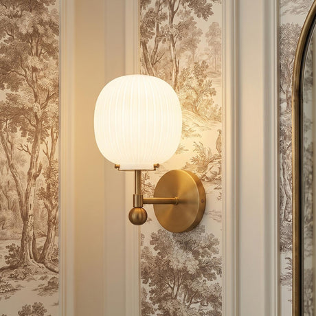 A traditional foyer with a Basile Wall Sconce 12 inch in brushed brass and ribbed milk glass mounted on sepia landscape toile wallpaper beside decorative molding.