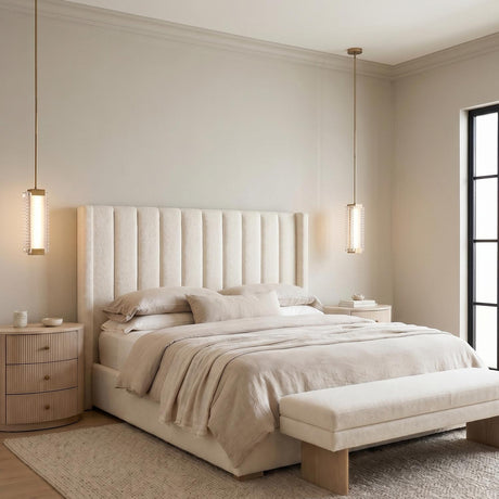 A contemporary bedroom with two vintage brass and clear ribbed glass pendants hanging over fluted wood nightstands flanking a channel-tufted upholstered bed near a large window.