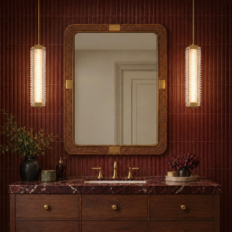 A contemporary bathroom features two Enders Large LED Pendants in vintage brass and clear ribbed glass flanking a woven mirror over a red marble vanity.