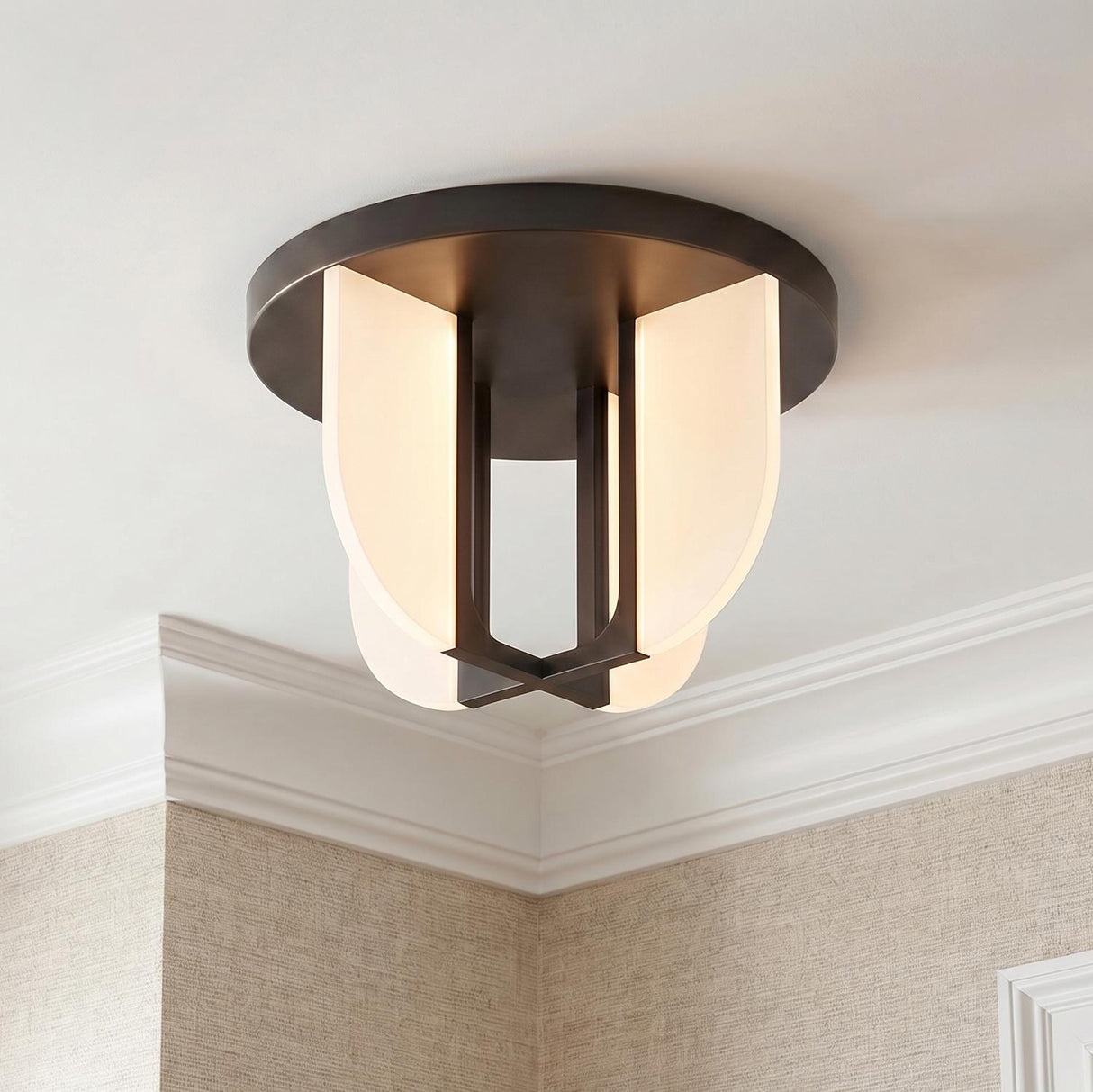 A transitional foyer with the Dagan LED Flush Mount featuring an urban bronze finish and frosted glass panels along the ceiling above tan textured wallpaper and crown molding.