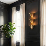 A traditional living room featuring the Zora 3 Light Wall Sconce 28", Polished Brass on charcoal paneled walls next to white linen curtains and a fiddle leaf fig.