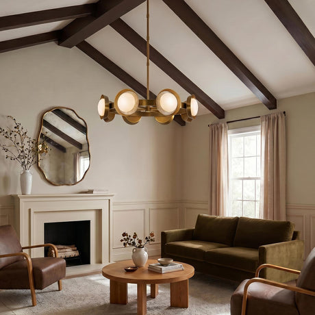 A transitional living room featuring the Osmund LED Chandelier 37", Vintage Brass with frosted glass discs hanging from a sloped beamed ceiling above a green velvet sofa.