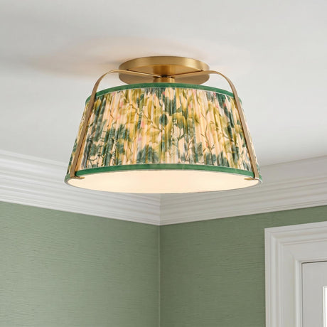 A traditional bedroom with a brushed brass and green floral fabric semi-flush mount installed on a standard ceiling above green grasscloth wallpaper and white crown molding.
