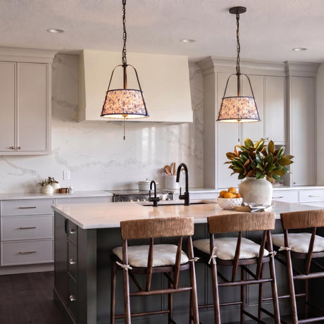 A transitional kitchen with two Daina Pendants in matte black and blue floral fabric over a white marble island featuring taupe cabinetry and a marble backsplash.