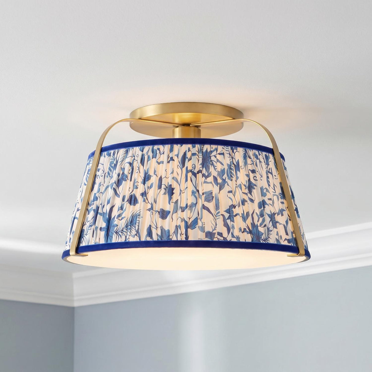 A traditional bedroom with the Daina Semi-Flush 13", Brushed Brass and Blue Floral mount installed on a white ceiling with crown molding and light blue walls.