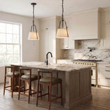 A transitional kitchen with two Daina Pendant 13", Matte Black and White fixtures over a white marble island with wood stools and cream-colored cabinets.