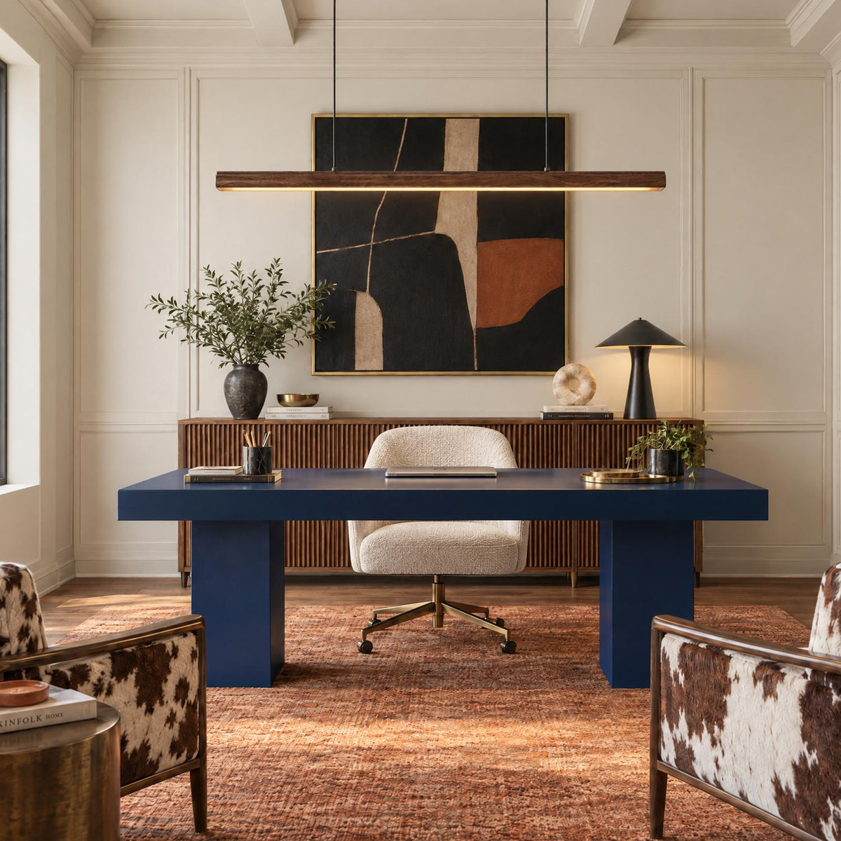 A contemporary office features the Jacob Linear LED Pendant 48", Walnut hanging over a navy blue desk in front of a fluted wood credenza beneath coffered ceilings.