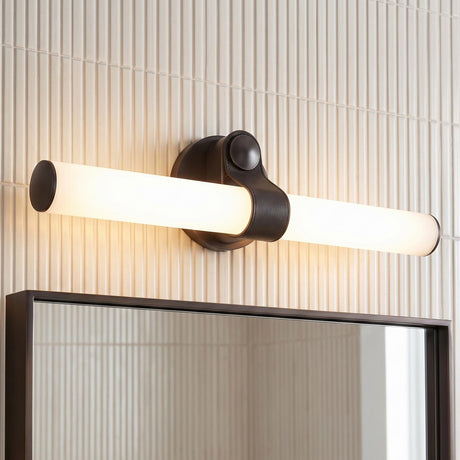 A modern bathroom features the Bodhi LED Wall Light in urban bronze and frosted glass mounted above a dark-framed mirror against vertical white kit-kat wall tiles.
