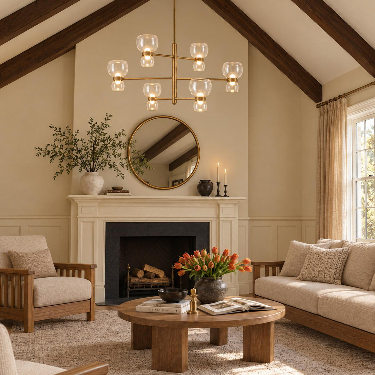A transitional living room features the Brann LED Chandelier 36", Vintage Brass and Clear Glass hanging from a vaulted beamed ceiling above a fireplace and wooden coffee table.