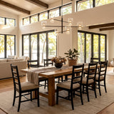 A modern farmhouse dining room featuring a dark bronze chandelier with clear glass shades hanging over a light wood dining table under exposed ceiling beams.