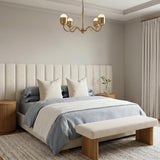 A transitional bedroom featuring a brushed brass Rubina 4 Light Chandelier 27" centered over a bed with a tall fluted headboard and light blue bedding.