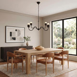A contemporary dining room with the Rubina 4 Light Chandelier in matte black centered over a light wood dining table and cognac leather chairs.