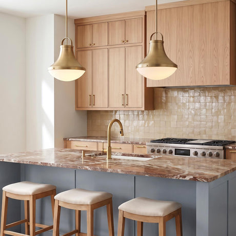 A contemporary kitchen with the Georgia Pendant 14", Aged Brass and Opal Glass hanging over a brown marble island with light wood cabinets.