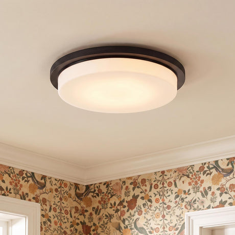 A transitional foyer features the Martine LED Flush Mount 16", Matte Black and Opal Glass mounted on the ceiling above floral wallpaper and white crown molding.