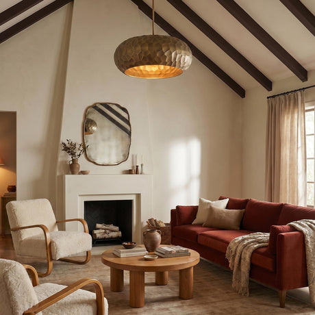 A transitional living room with the Benicio Pendant 26" in burnished patina brass suspended from a vaulted beamed ceiling over a rust velvet sofa and sherpa chairs.