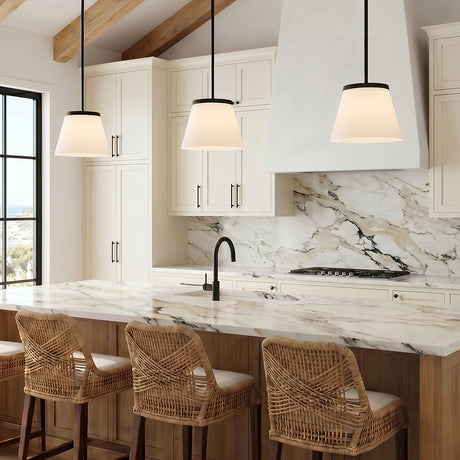 A modern farmhouse kitchen with three matte black and opal glass pendants over a marble island with woven wicker stools under a vaulted beamed ceiling.