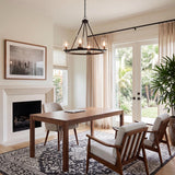 A transitional home office featuring the Darlene 4 Light Chandelier 28", Matte Black suspended over a wooden desk near mid-century armchairs and a fireplace.