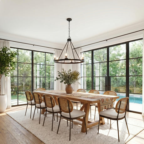 A modern farmhouse dining room featuring a matte black Darlene 6 Light Chandelier 36" over a long wood table with woven rattan chairs and large black-framed windows.