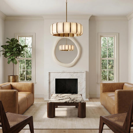 A contemporary living room with a Cian LED Chandelier in aged brass and milk glass over a marble coffee table, tan leather sofas, and an organic-shaped mirror.