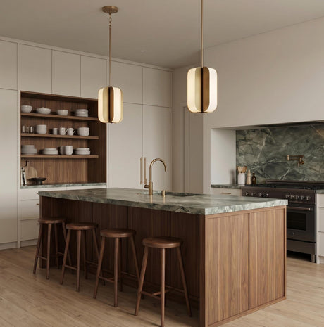 A modern kitchen with two Cian LED Pendant 12" fixtures in aged brass and milk glass over a walnut island and green marble countertop with white cabinets.