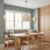A transitional dining room with an aged brass and ivory beaded pendant over a light wood table with matching wall sconces and built-in wood cabinets.