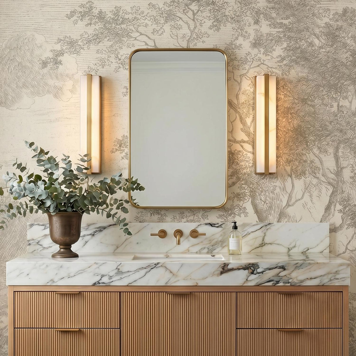 A transitional bathroom with two Azura LED Vanity 24" lights in aged brass and alabaster flanking a mirror above a marble countertop and fluted vanity.