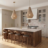 A transitional kitchen with two natural wooden bead cone pendants in a matte brass finish hanging over a walnut wood island with pink marble countertops and backsplash.