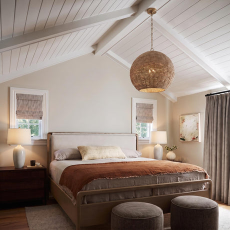 A coastal bedroom features a woven globe pendant suspended from a brass chain under a white vaulted beamed ceiling above a wood bed.