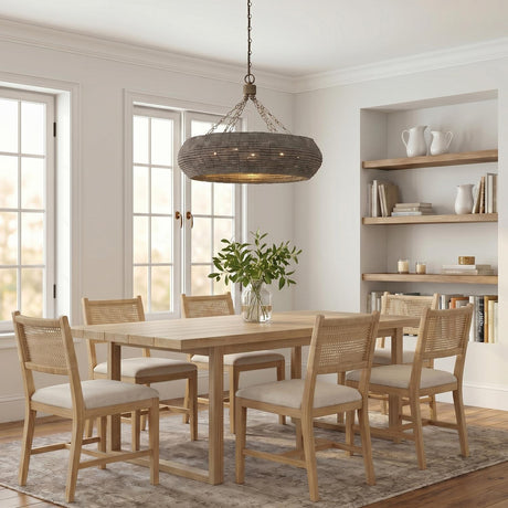 A coastal dining room with the Esmara Chandelier in gray wash wooden beads over a light wood table and cane-back chairs beside built-in wood shelving.