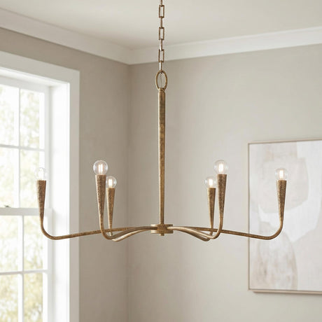 A transitional living room featuring the Myra 6 Light Chandelier 39", Artisan Brass in a textured finish suspended from the ceiling center near a large white-trimmed window.