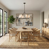 A modern farmhouse dining room with the Gerald 6 Light Chandelier, Matte Black and Hammered Brass over a light wood table and woven cane back chairs.