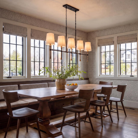 A modern farmhouse dining room with the Gerald Linear Chandelier in matte black and hammered brass suspended over a walnut table with built-in banquette seating.