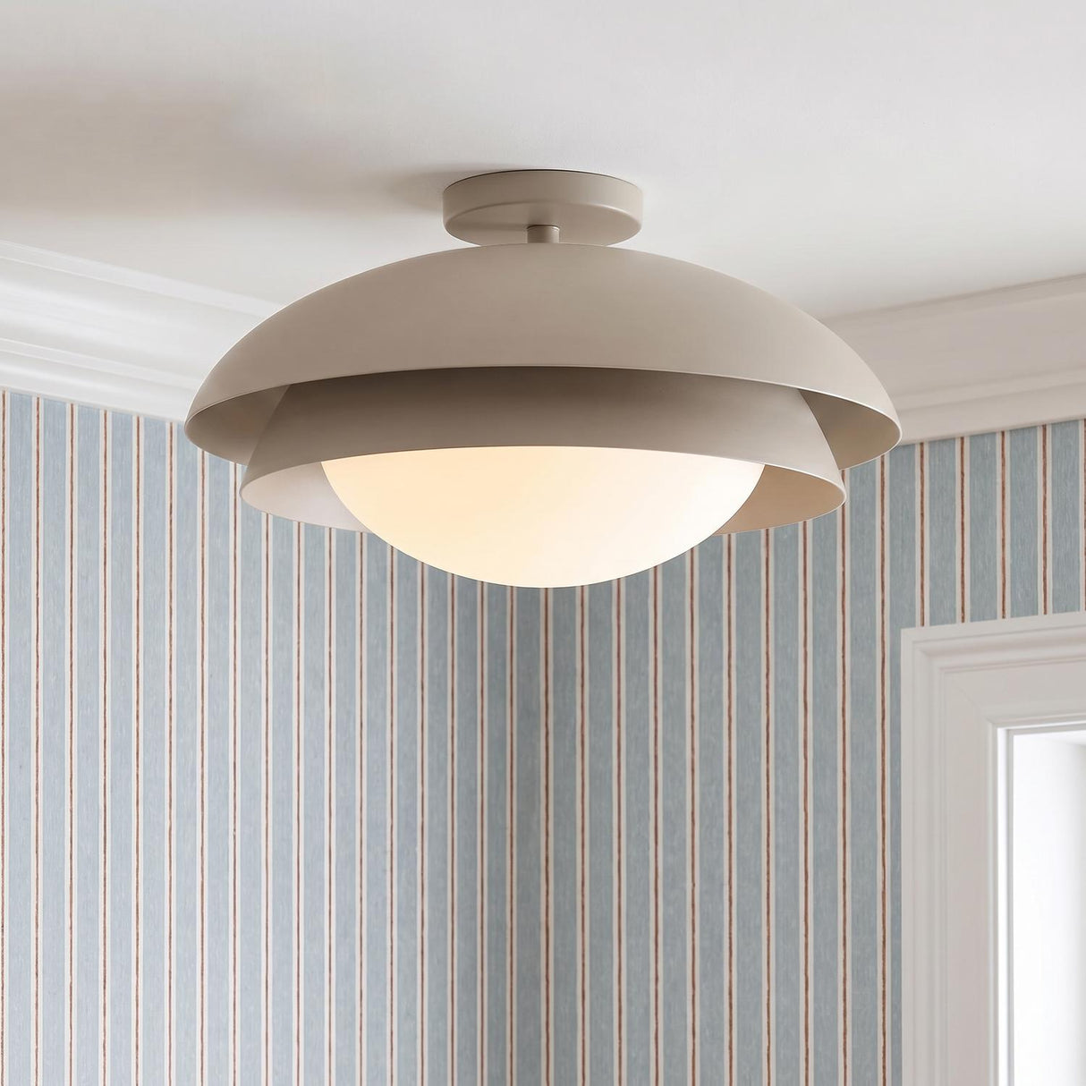 A transitional foyer featuring the Ruperto Semi-Flush in taupe and opal glass mounted to the ceiling with blue and white striped wallpaper and white crown molding.