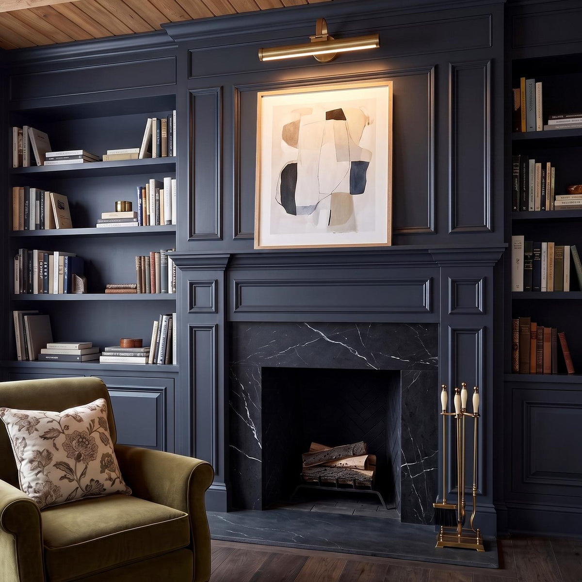 A transitional living room with the Sterling LED Picture Light 22 inch in matte brass mounted above an abstract painting and a black marble fireplace.