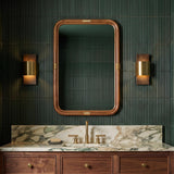 A modern bathroom with the Solace LED Wall Sconce in espresso wood and matte brass flanking a mirror over a marble vanity and fluted tiles.