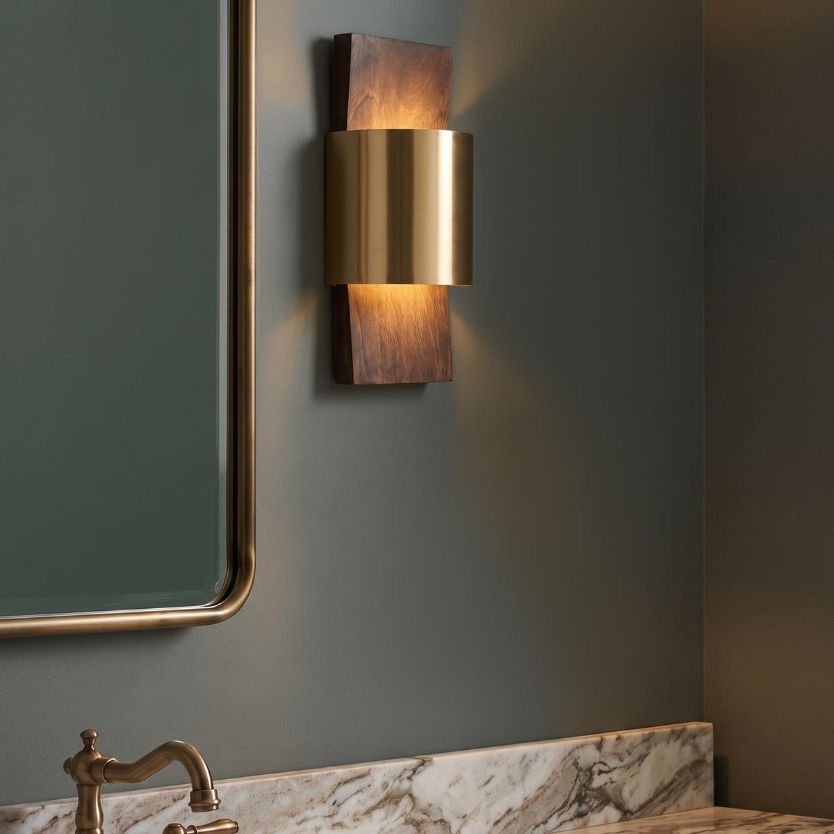 A mid-century bathroom with the Solace LED Wall Sconce in espresso wood and matte brass mounted beside a brass-rimmed mirror above a marble vanity with a matching faucet.
