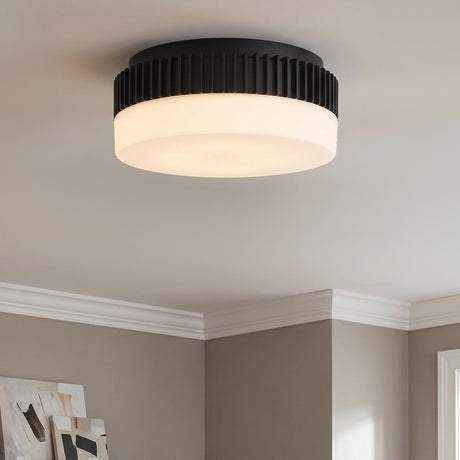A modern living room with a Jamel Medium LED Flush Mount 12" in matte black and opal glass on the ceiling above taupe walls and crown molding.
