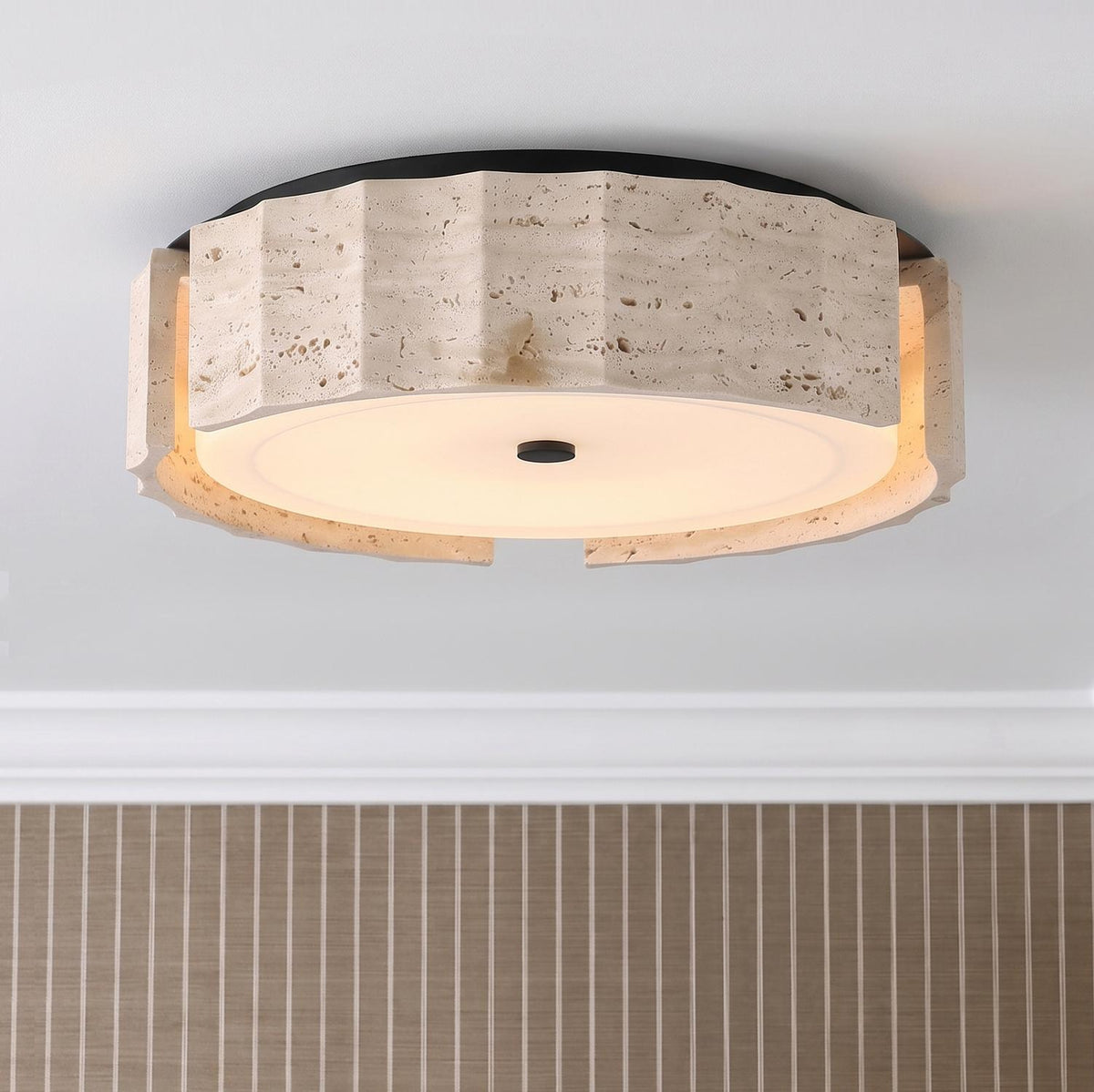 A modern foyer with the Damari Medium LED Flush Mount in travertine and matte black along the ceiling above vertical striped tan wallpaper and white molding.