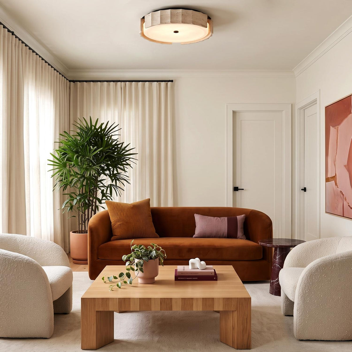 A contemporary living room with the Damari Large LED Flush Mount 24" in travertine and matte black on the ceiling above a rust velvet sofa and chairs.