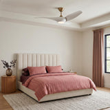 A modern bedroom with the Krestel LED Ceiling Fan 52", Matte White and Modern Brass centered on the ceiling above a cream channel-tufted headboard and terracotta bedding.