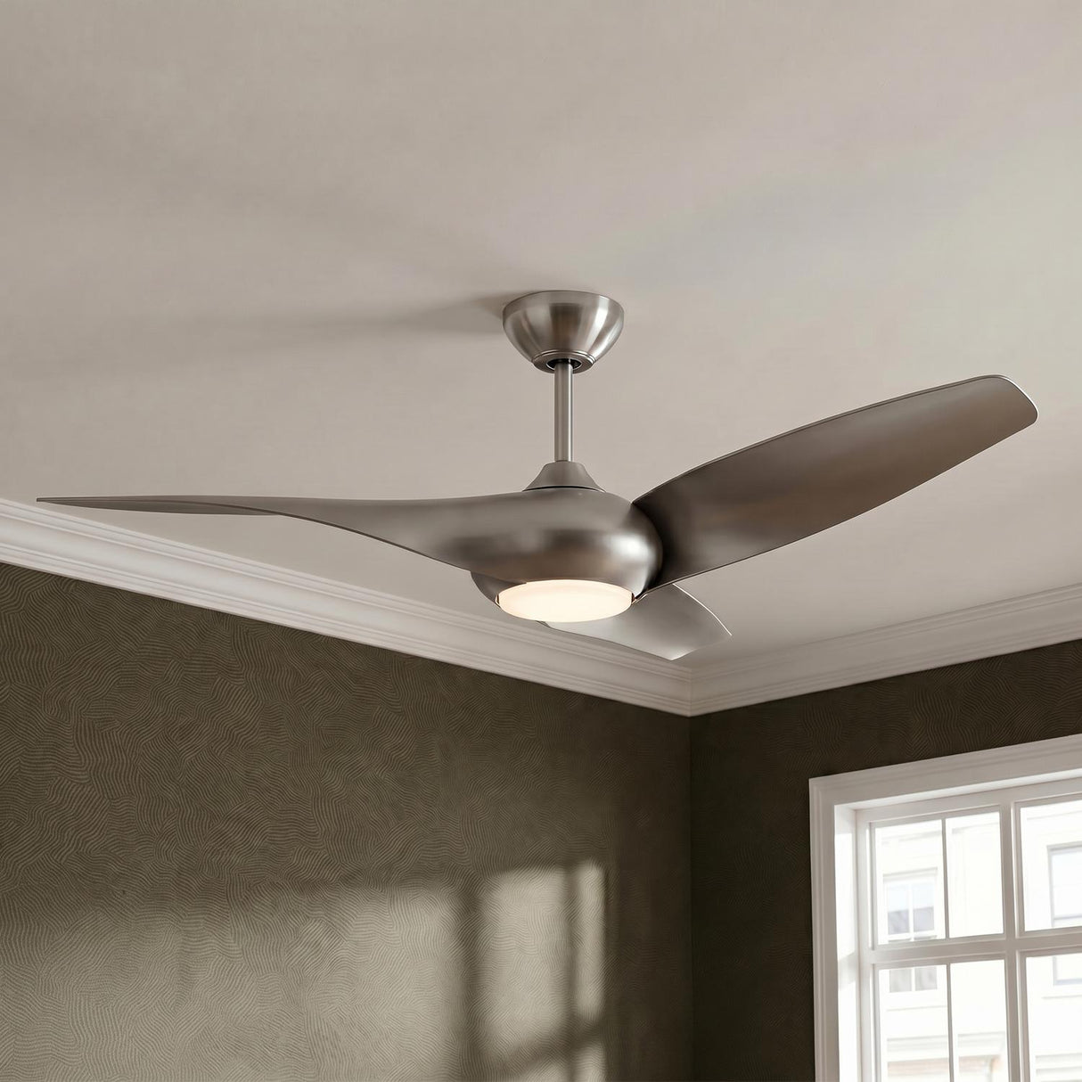 A contemporary bedroom with the Krestel LED Ceiling Fan 52" in brushed steel and frosted glass centered on the ceiling above textured wallpaper and white crown molding.
