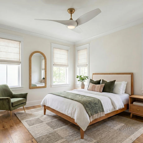 A modern bedroom featuring the Krestel LED Ceiling Fan with matte white blades and a modern brass finish installed above a light wood bed and area rug.