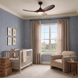 A transitional nursery with the Egret LED Ceiling Fan 44", Walnut Wood and Matte Black at the ceiling center, featuring blue floral wallpaper and a gray crib.