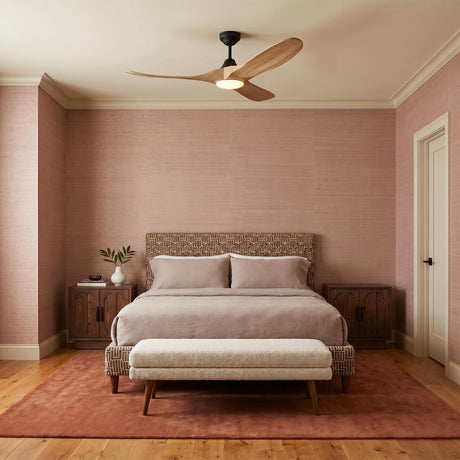A mid-century bedroom with the Egret LED Ceiling Fan 52" in natural oak and matte black centered over a bed against pink grasscloth wallpaper and wood floors.